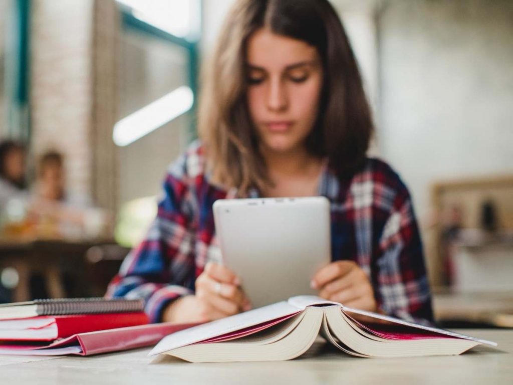 Mani che scrivono su un laptop con libri e testo "Obiettivi Generali e Specifici nella Tesi di Master"