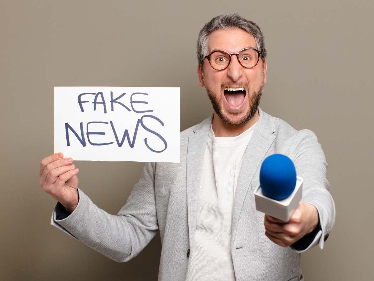 Giornalista con cartello 'Fake News' e microfono blu